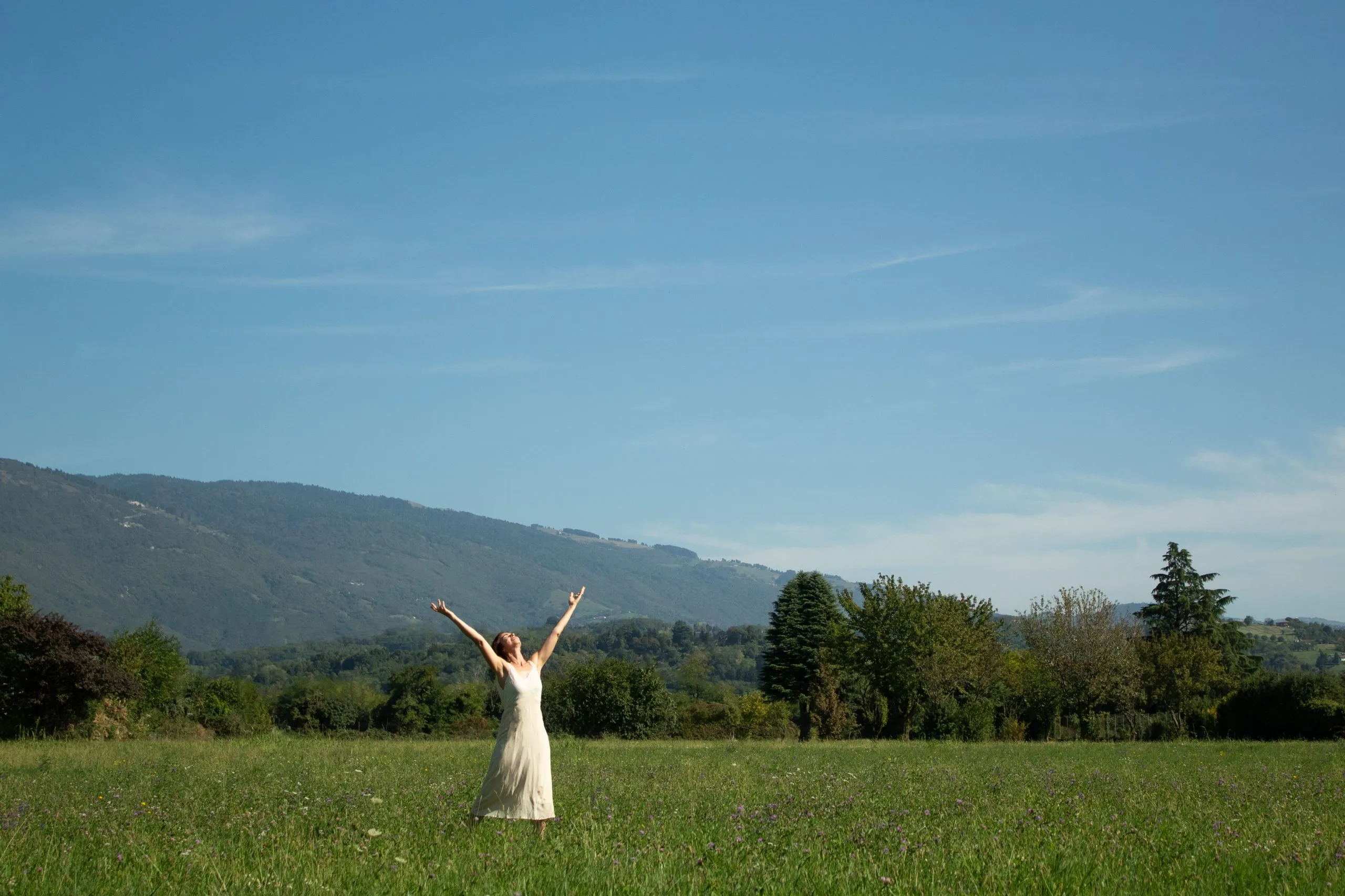 Barbara in un prato con le braccia alzate verso il cielo, davanti alle montagne