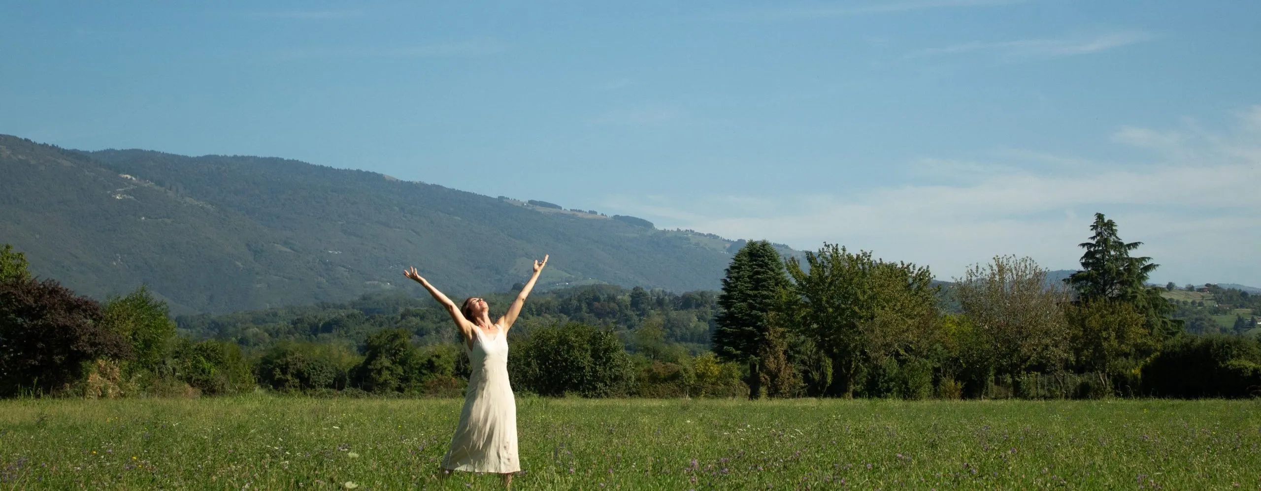 Barbara in un prato estivo con le braccia alzate verso il cielo